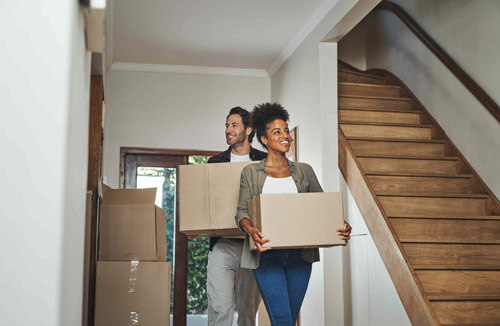 Happy couple moving boxes into empty home